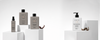 Beige and gray haircare bottles arranged on white display blocks