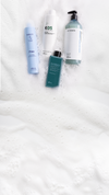 Assorted Kaaral shampoo bottles arranged on white foam with open space below for banner content.