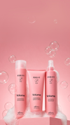 Purify Volume haircare products displayed on a pink pedestal with foam and translucent bubbles against a pink background.