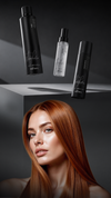 Gloss and heat protection haircare products floating above a model with long straight copper hair against a dark studio background.