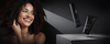 Smiling curly-haired woman beside black haircare products