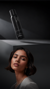 Brunette model below a black haircare product bottle